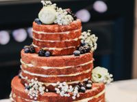 naked three tier wedding cake with berries and flowers