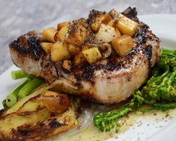 dinner plate of grilled pork chop with broccoli and baked apple chutney